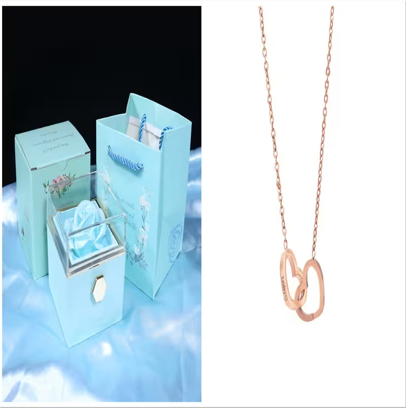 Rose gold necklace with heart-shaped pendants in a blue jewelry box on a white background
