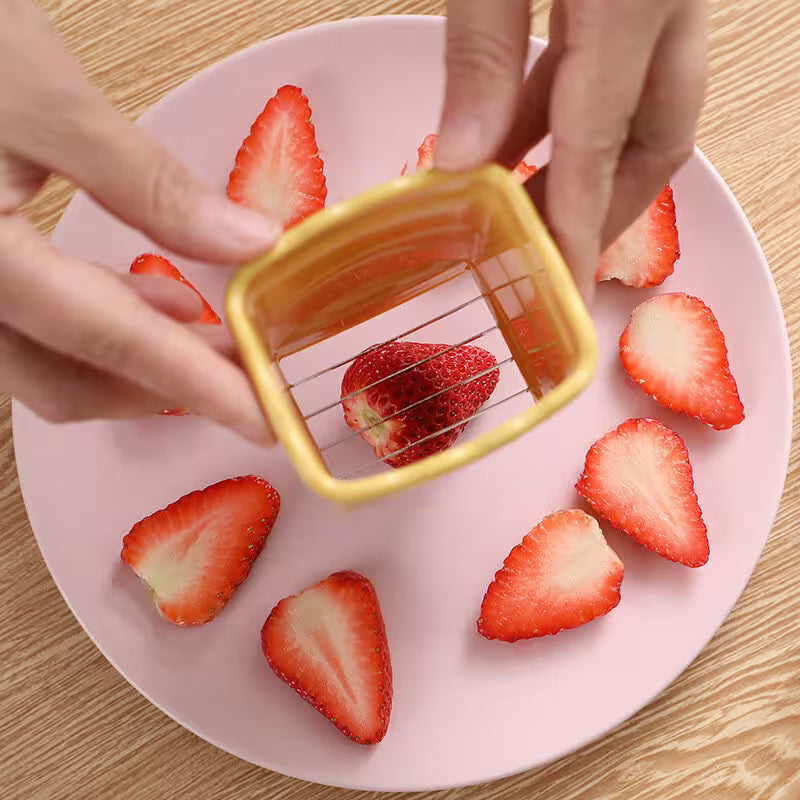 Strawberries being cut with a small square knife on a pink plate.