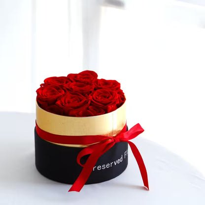 Round box with red roses and a red ribbon on a white background