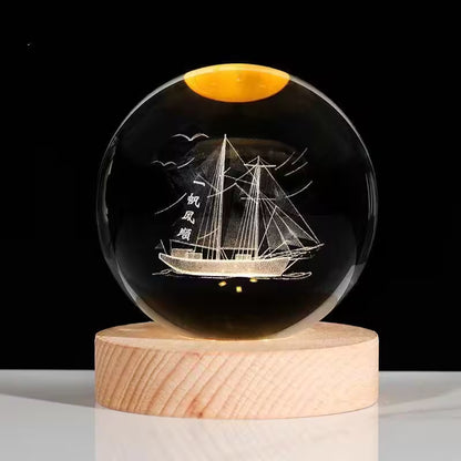Cylindrical glass object with ship engraving on a wooden base against a black background