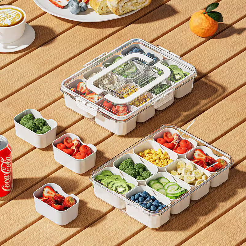 Meal prep containers with compartments filled with fruits and vegetables on a wooden table.