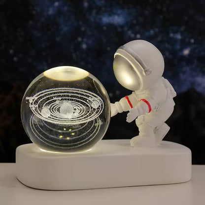Astronaut figurine interacting with a crystal ball displaying a solar system model on a dark background.