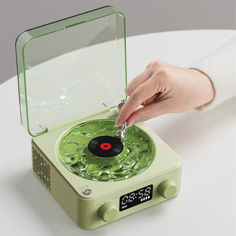 Green record player with a hand interacting with it on a white surface