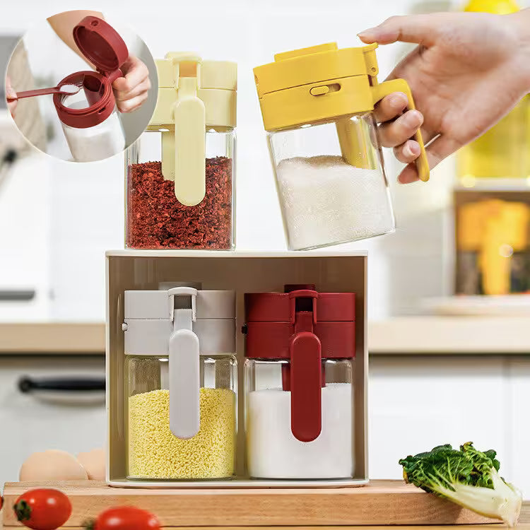 Set of four colorful spice containers with a hand holding one, on a kitchen counter.