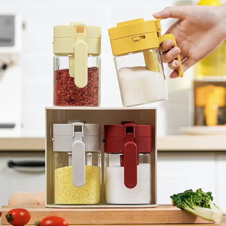 Set of four colorful spice containers on a kitchen counter with a hand reaching for one of them.