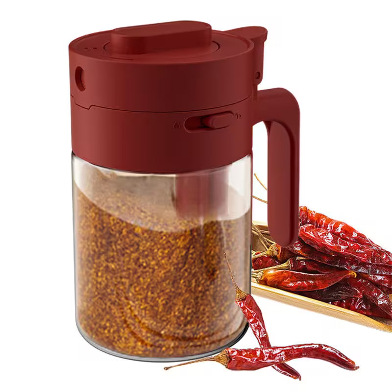 Red spice jar with a handle next to dried red chilies on a white background