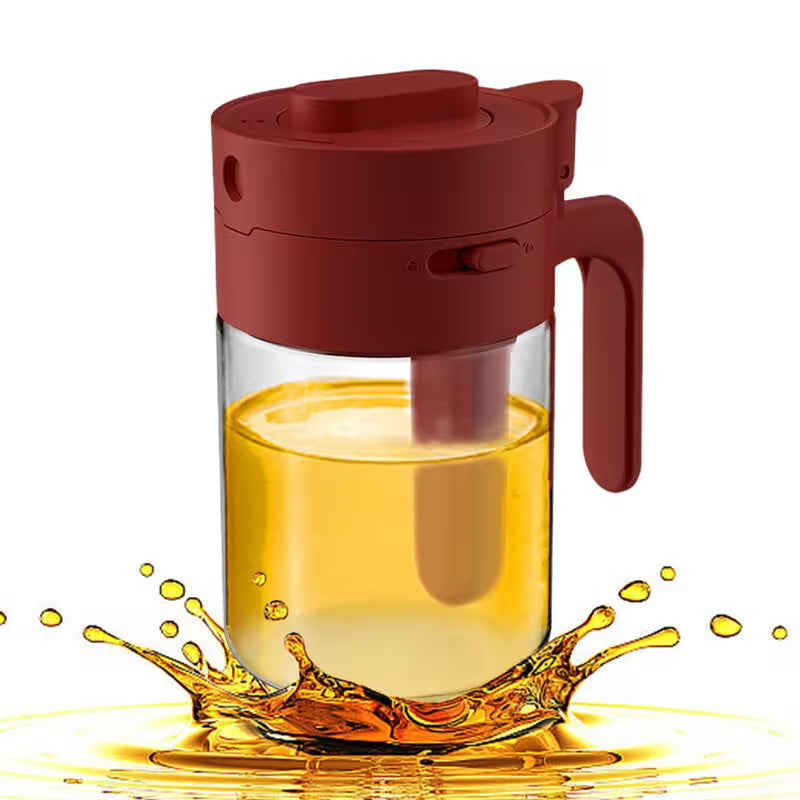 Red glass pitcher with a handle filled with yellow liquid on a white background