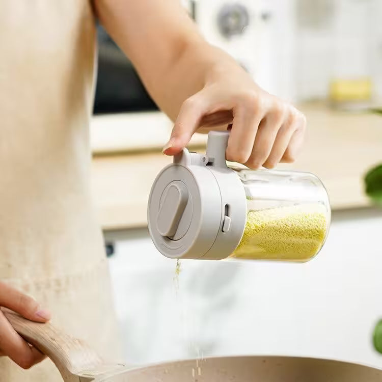 Person holding a glass container with a white lid, filled with yellow powder, in a kitchen setting.