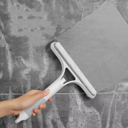 Person using a squeegee to clean a glass surface with soapy water.