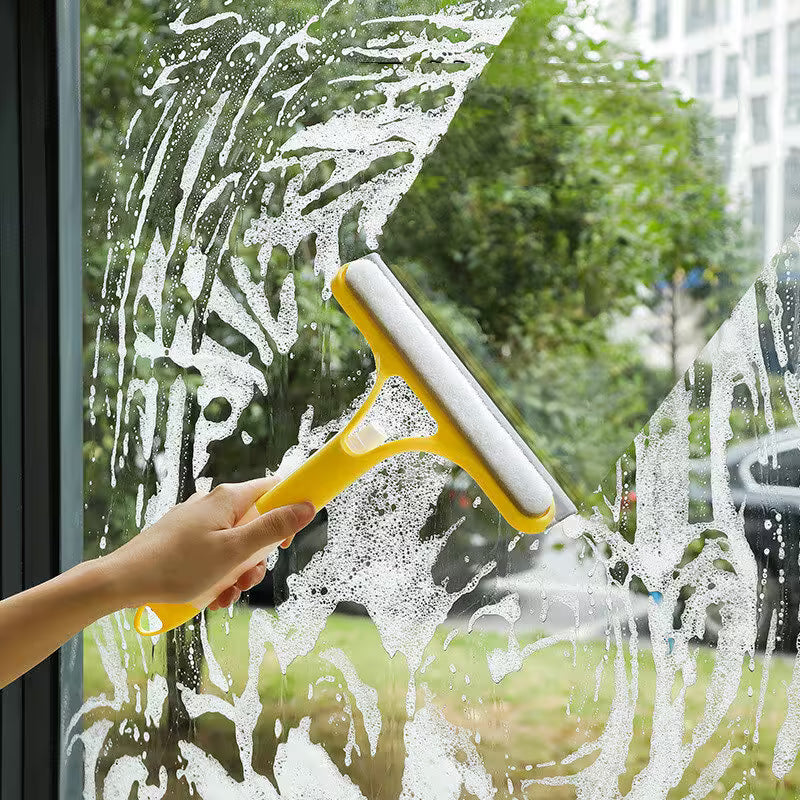 Person cleaning a window with a yellow squeegee
