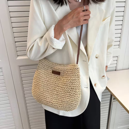 Person wearing a white blazer with a straw handbag against a neutral background