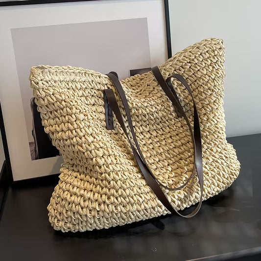 Woven beige bag with brown handles on a dark surface