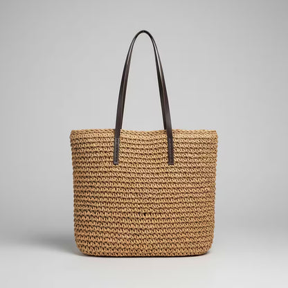Woven straw tote bag with black handles on a light gray background