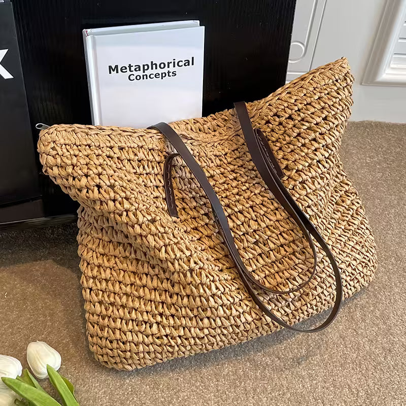 Woven straw bag with brown leather straps on a carpeted floor.