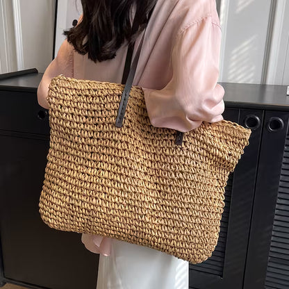 Person holding a woven handbag in front of a black background