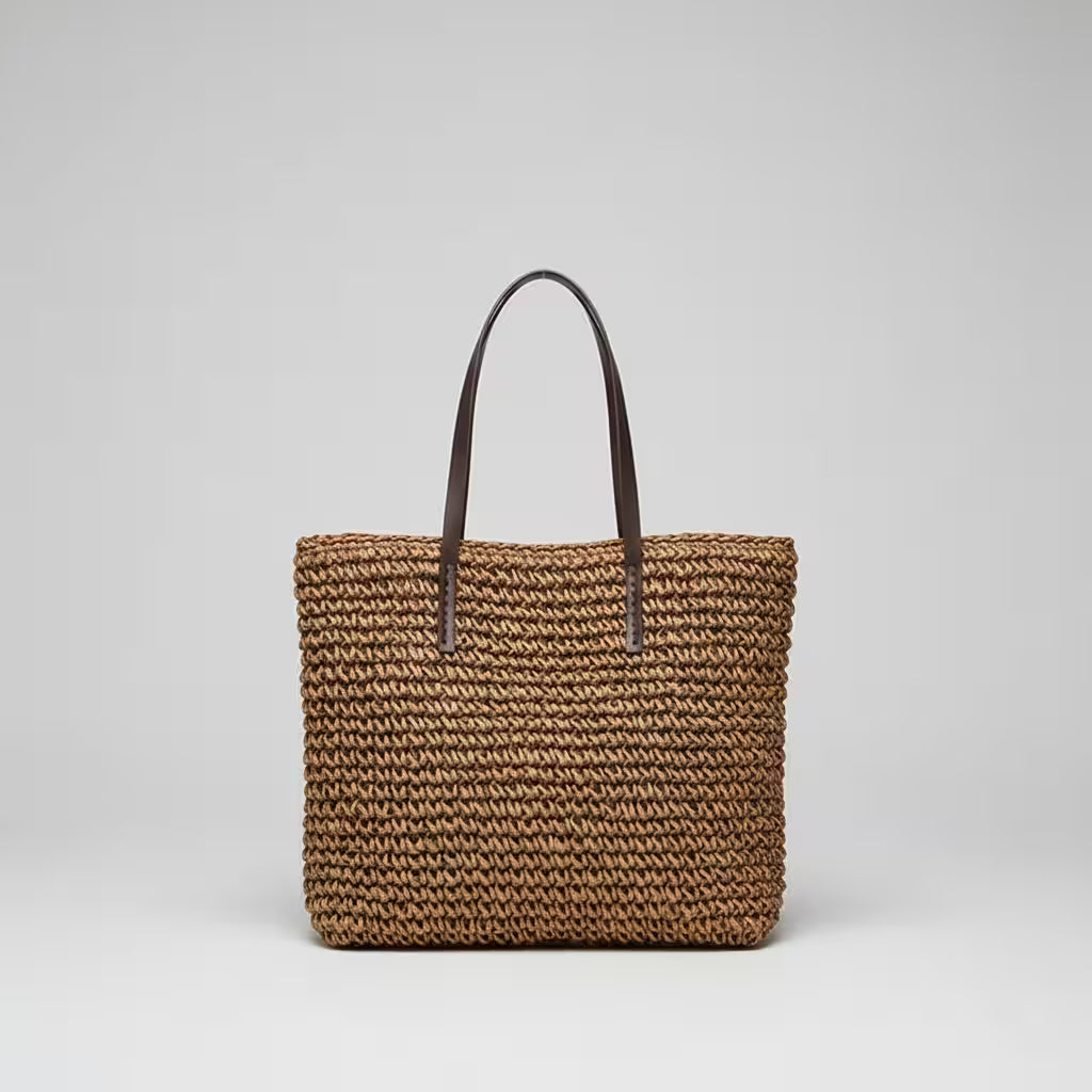 Woven brown bag with a black handle on a light gray background