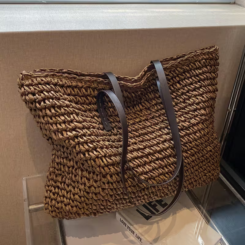 Woven handbag with leather straps on a glass surface