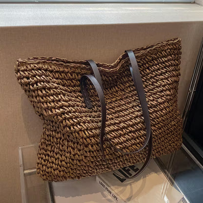 Woven handbag with leather straps on a glass surface