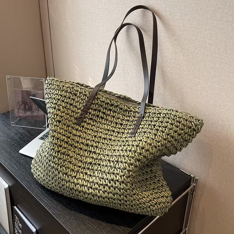 Green woven bag with brown leather straps on a wooden surface.
