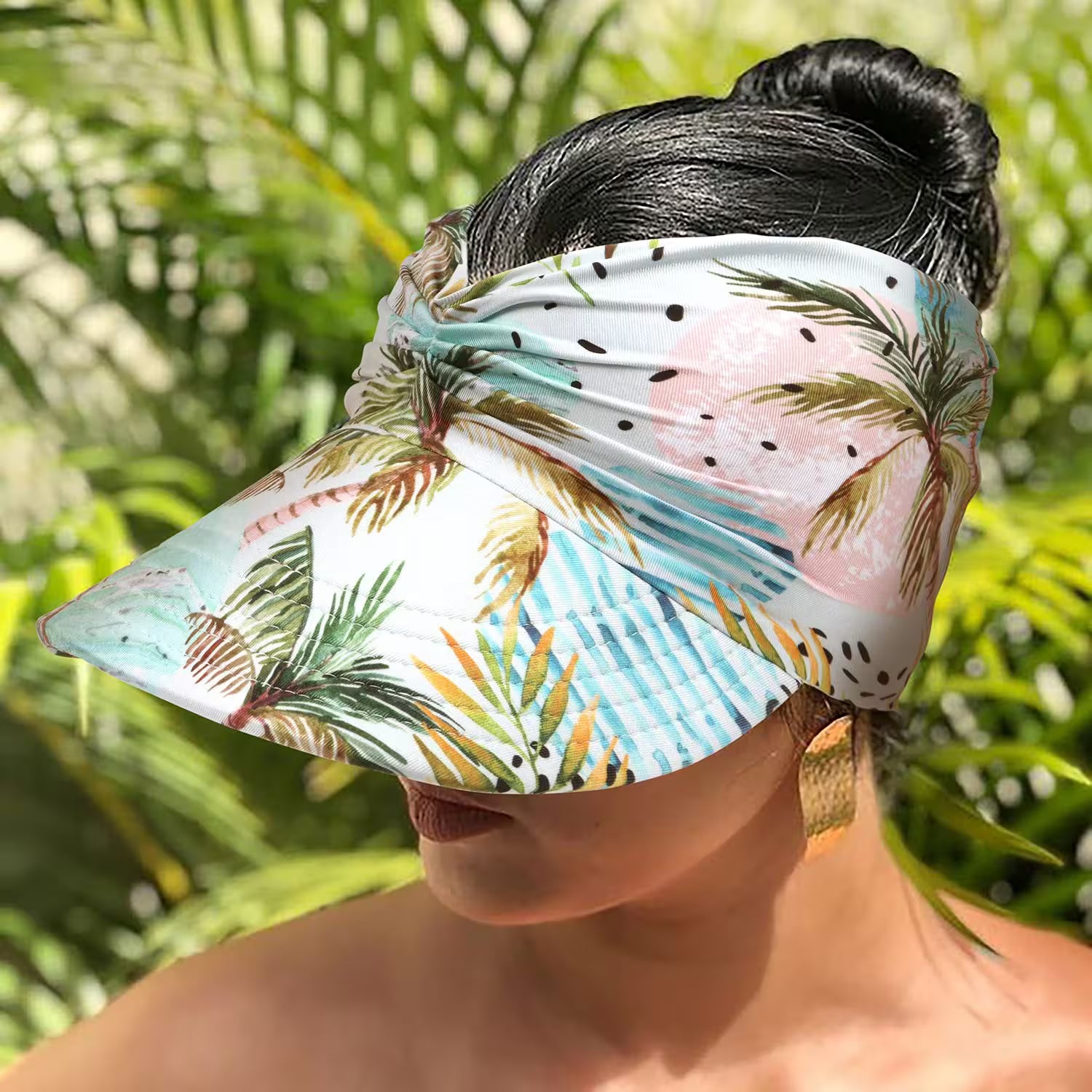 Person wearing a tropical patterned visor with palm trees and polka dots against a blurred green background.