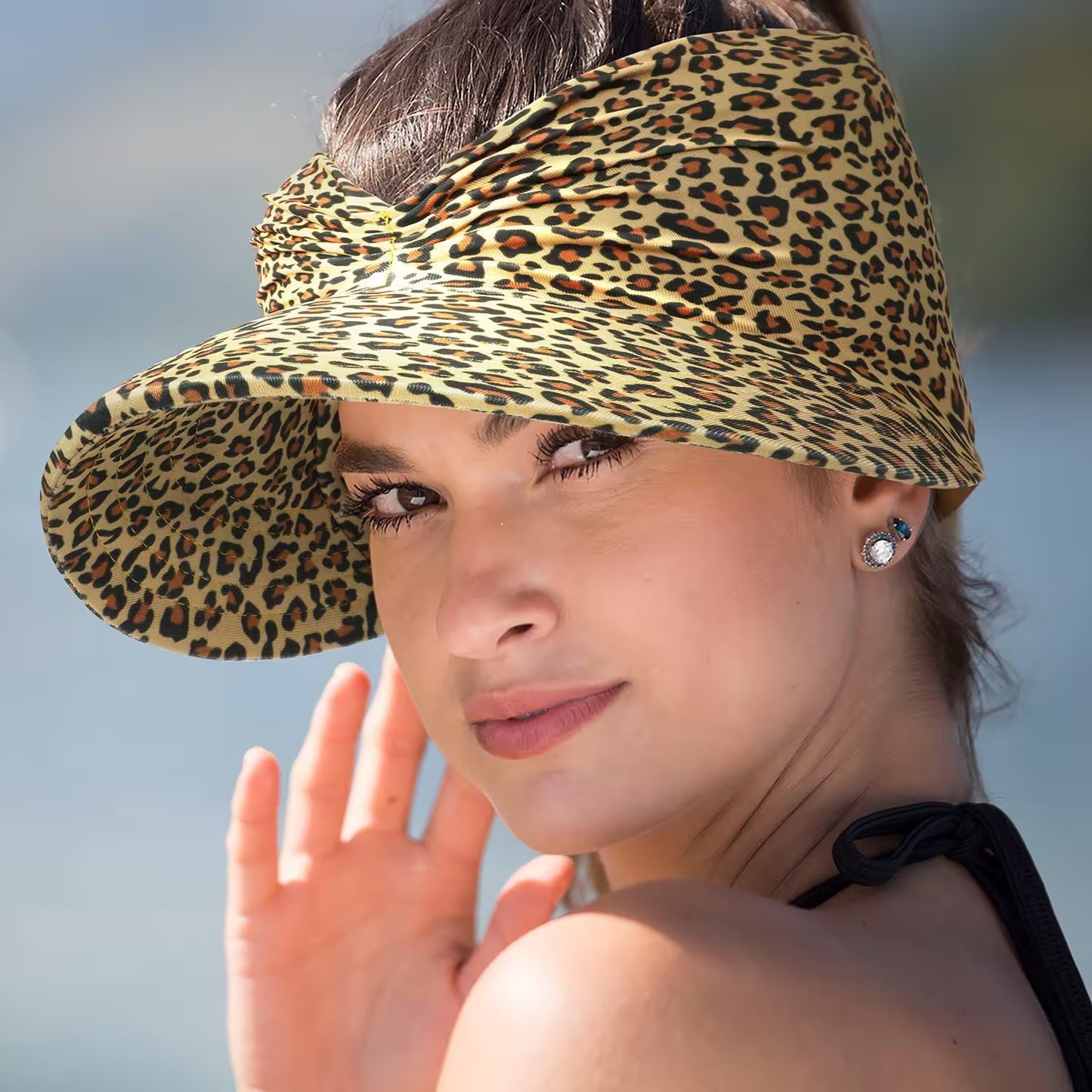 Woman wearing a leopard print visor hat with a blurred background