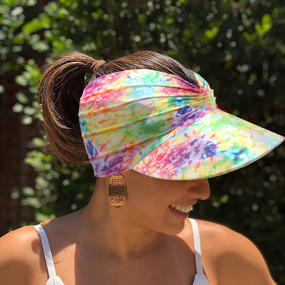 Woman wearing a colorful tie-dye visor with a blurred green background