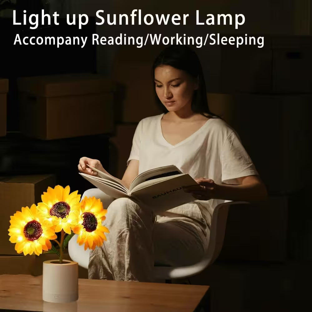 Woman reading a book with a sunflower-themed lamp on a table next to her.