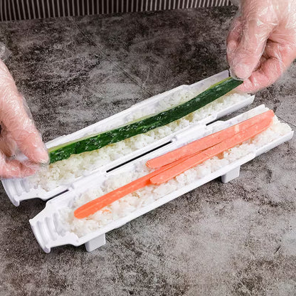 Hands preparing sushi with a rice mold and vegetable slices on a gray surface.