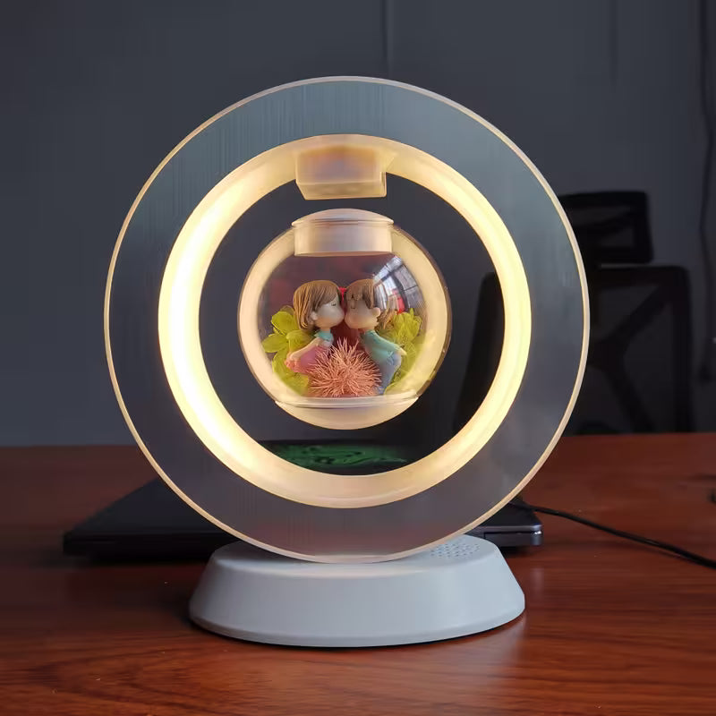 Decorative lamp with a glass sphere containing figurines on a wooden surface.