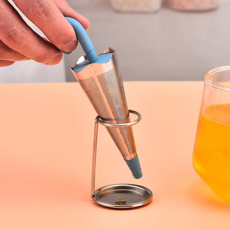 Tea infuser with blue handle being used over a glass of tea.