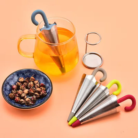Tea-making set with a cup of tea, tea leaves, and colorful tea infusers on a peach background.