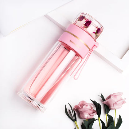 Pink glass water bottle with floral design on a white background