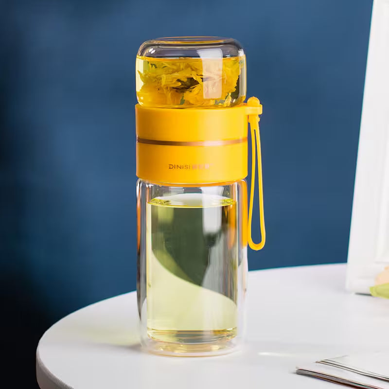 Clear water bottle with yellow lid and handle on a white surface against a blue background