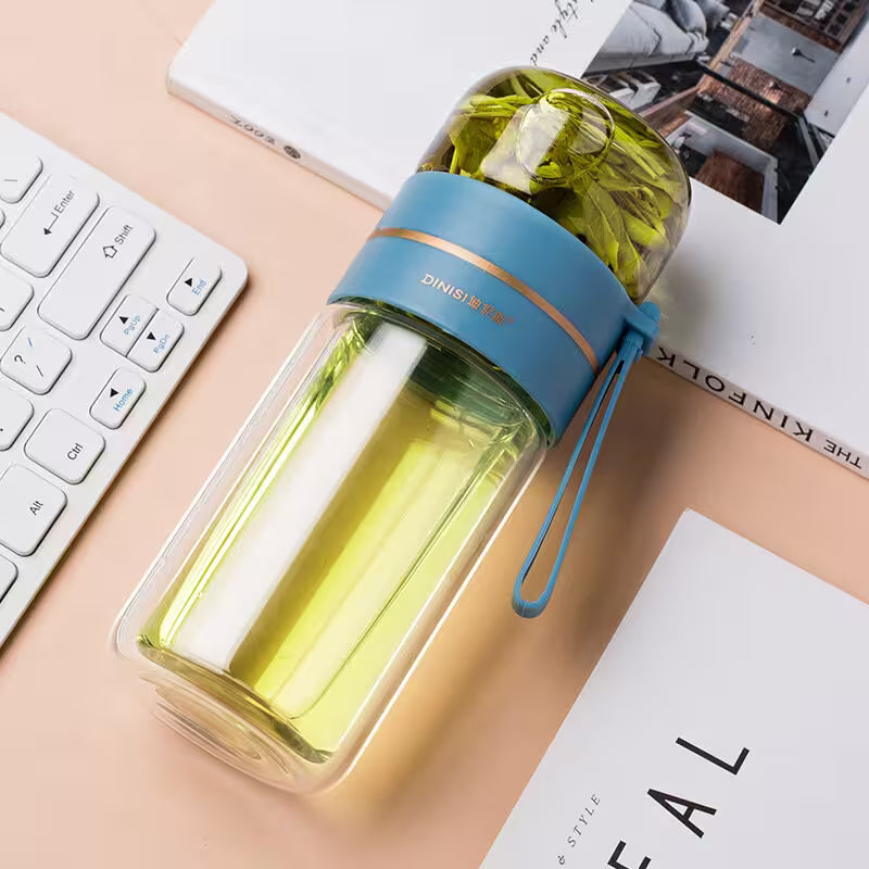 Clear water bottle with blue band on a desk with keyboard and magazine
