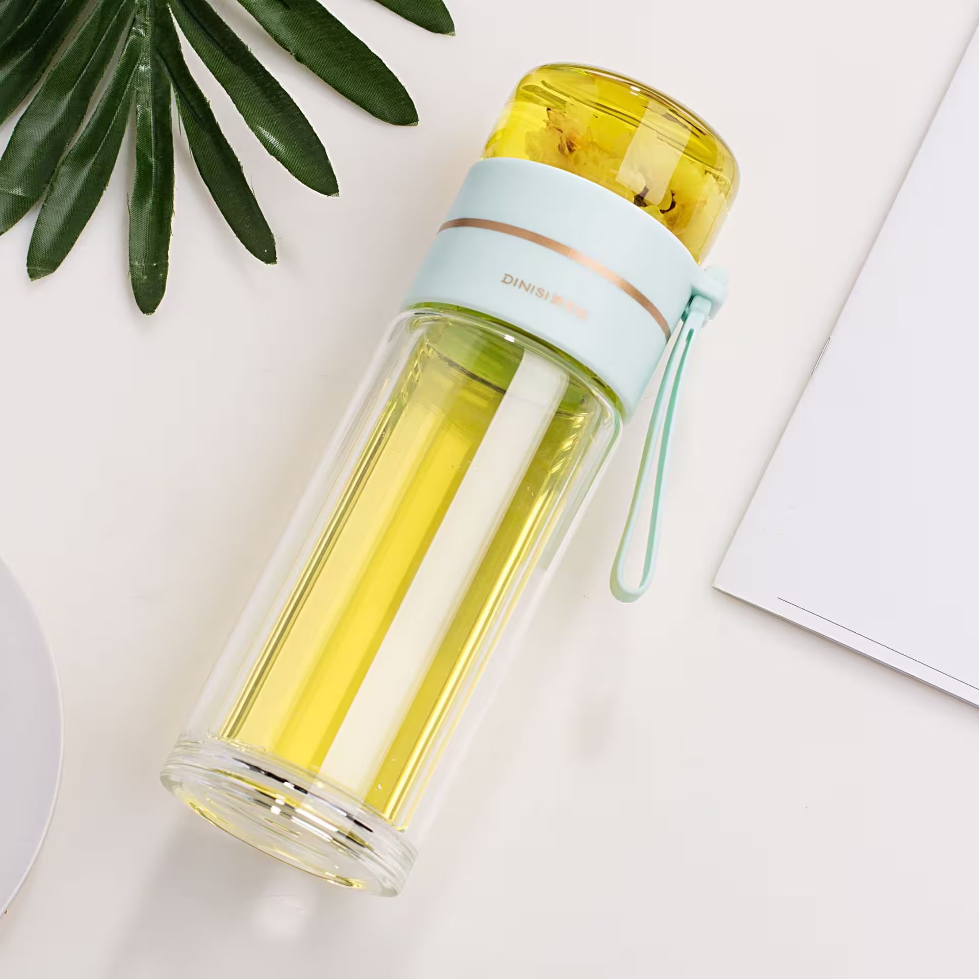 Clear water bottle with yellow liquid on a light surface with green leaves