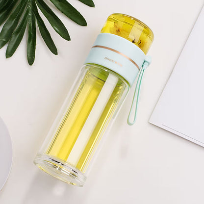 Clear water bottle with yellow liquid on a light surface with green leaves
