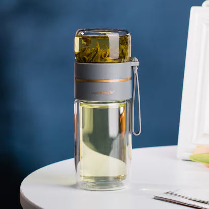 Clear glass bottle with tea leaves on a white surface against a blue background