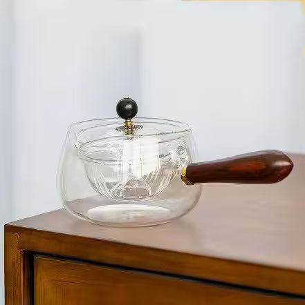 Clear glass teapot with wooden handle on a wooden surface