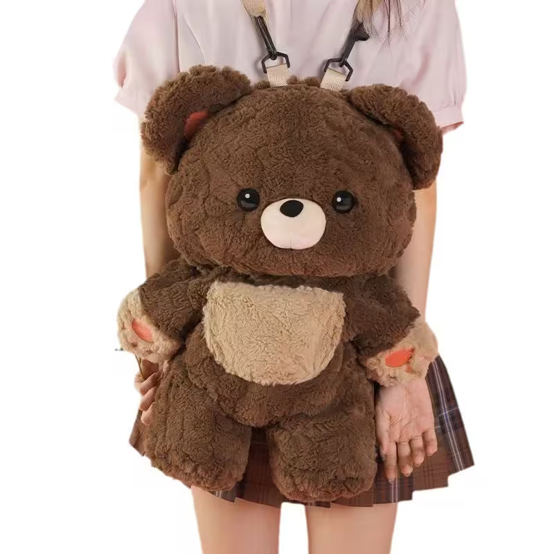 Brown teddy bear backpack held by a person wearing a white shirt and plaid skirt.