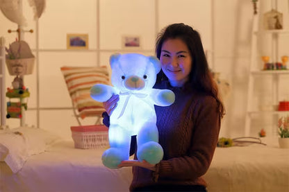 Woman holding a glowing teddy bear in a bedroom setting