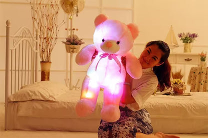 Person holding a large, glowing teddy bear in a bedroom setting