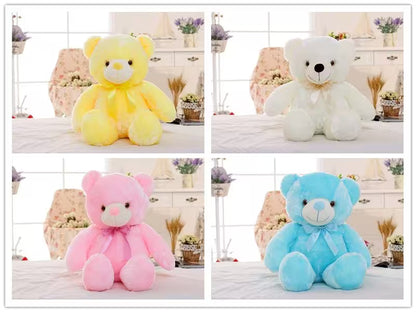 Four teddy bears in yellow, white, pink, and blue on a decorative background.