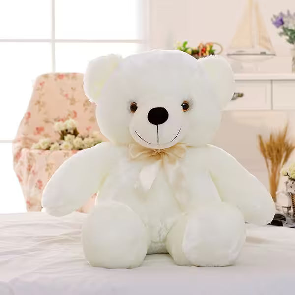 White teddy bear with a bow tie on a light-colored surface with a blurred background