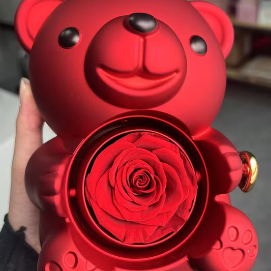Red teddy bear-shaped container with a rose inside, held by a hand.
