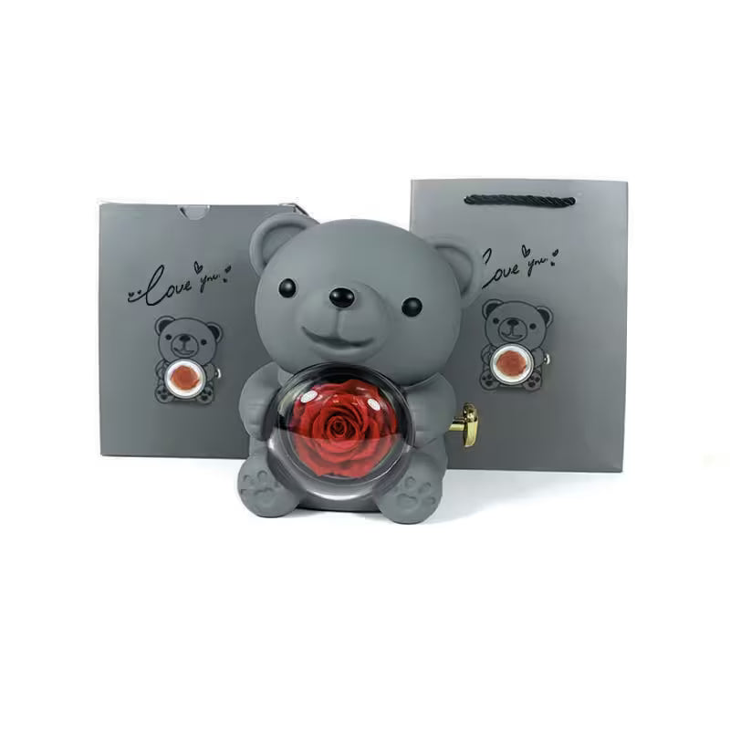 Gray teddy bear with a red rose inside, standing in front of two gray gift bags with teddy bear designs and 'I love you' text.