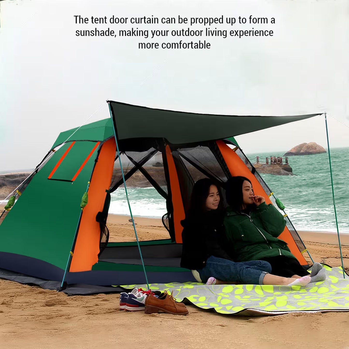 Two people sitting inside a tent on a beach with a sunshade, ocean view in the background.