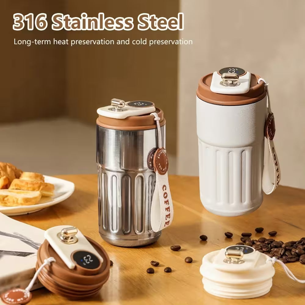 Two stainless steel coffee tumblers on a wooden table with coffee beans and pastries.