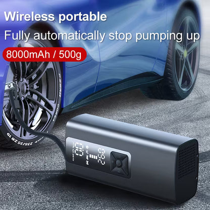 Wireless portable air pump with digital display next to a car tire on a road.