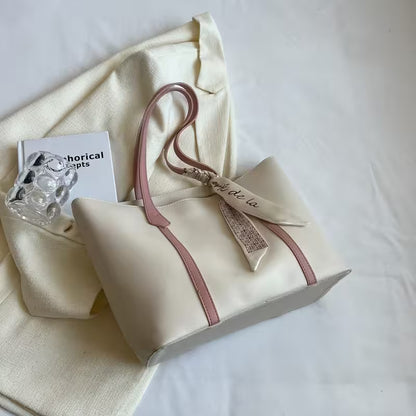 Beige handbag with pink strap on a white surface