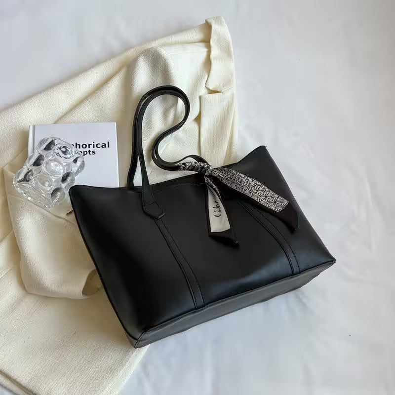 Black handbag with a decorative ribbon on a white surface